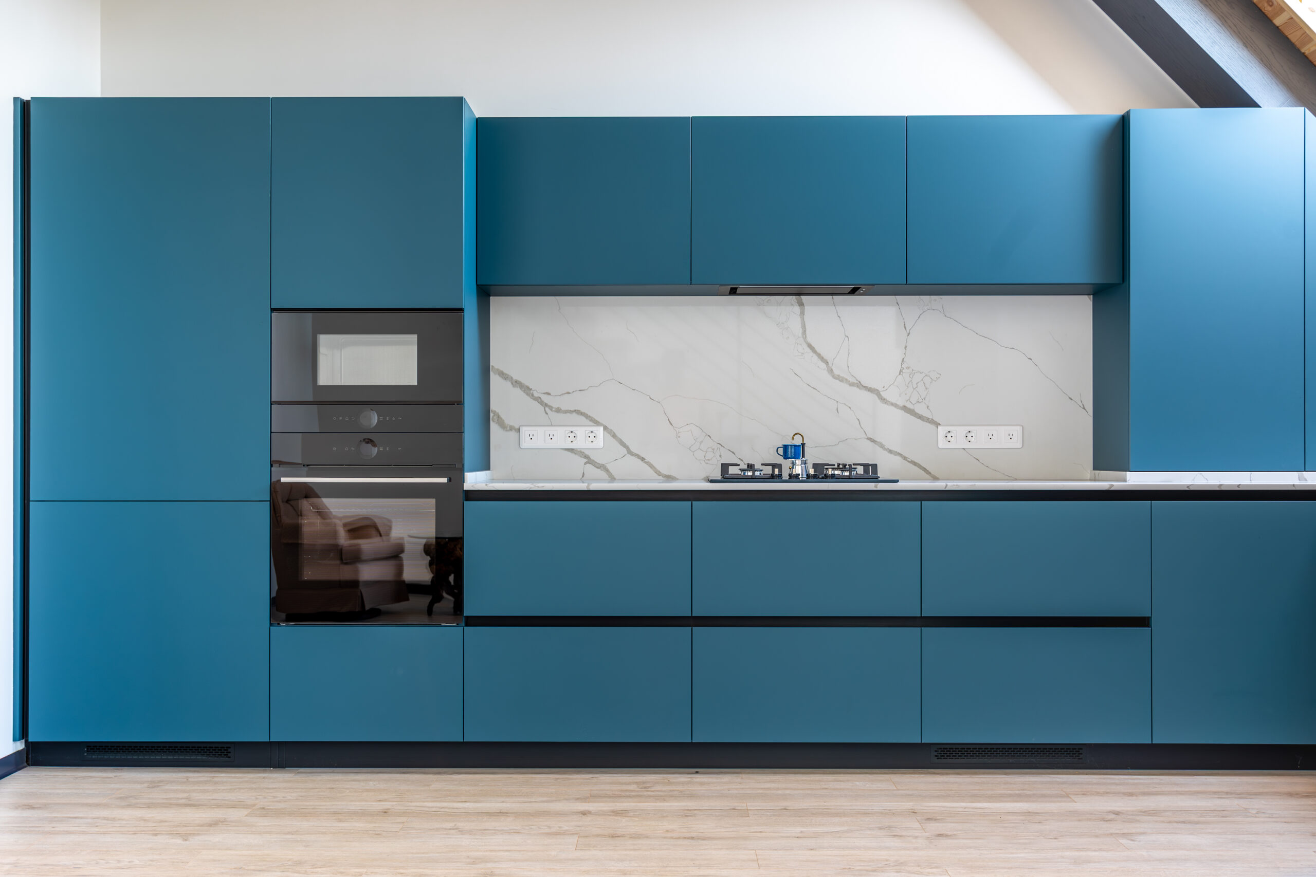 Modern matte blue frameless cabinets with integrated handles and a marble backsplash in a Charleston, SC kitchen remodel.